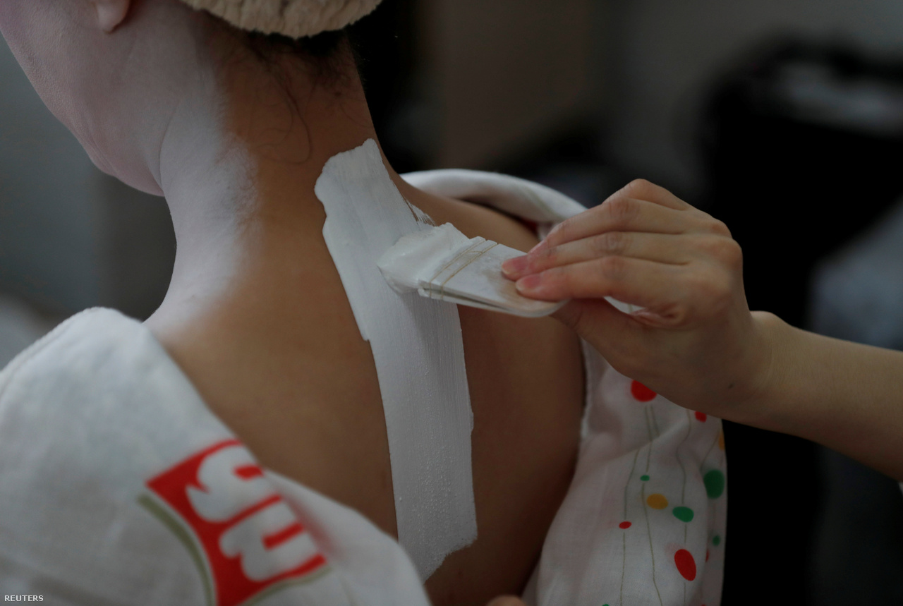Koyku paints Mayu Geisha's neck before performing in a restaurant where guests are entertained