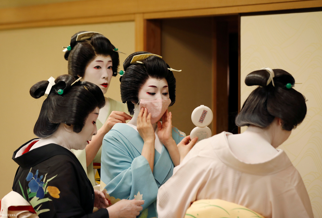 An adult geisha helps put on Koyku's protective mask