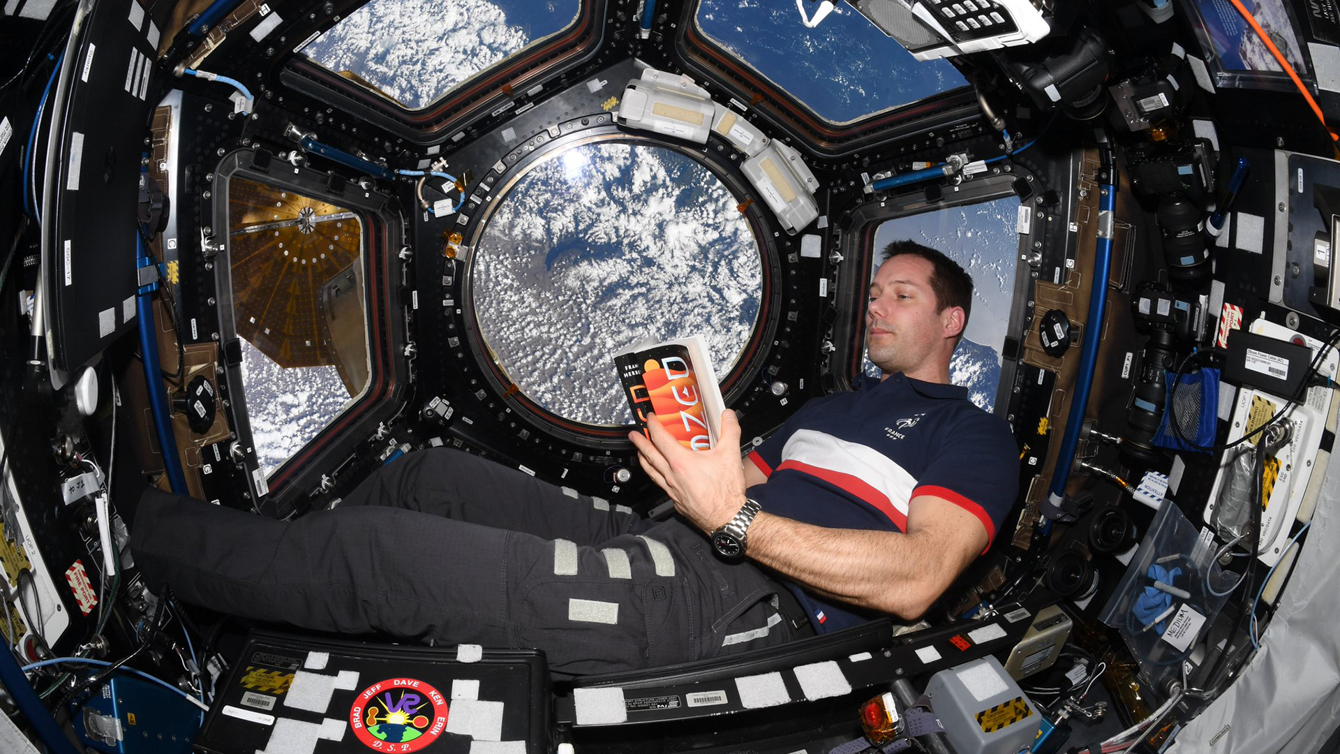 An astronaut takes a dune book to the International Space Station